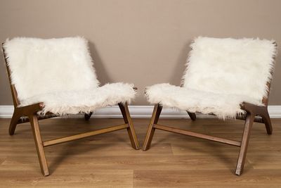 une paire de fauteuils en peau de mouton blanche devant un mur beige