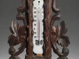 a wooden clock with a thermometer on top of it