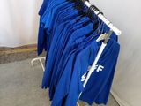de nombreuses chemises bleues suspendues à un portant dans une pièce