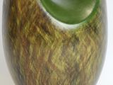 a green and brown vase sitting on a white surface