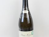 une bouteille de vin posée sur une table à côté d'un mur blanc