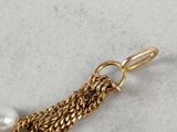 a close up of a gold chain with two pearls on it