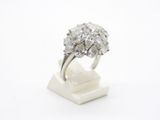 un gros plan d'une bague en diamant posée sur un socle, sur une surface blanche