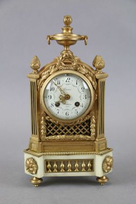a gold and white clock sitting on top of a table