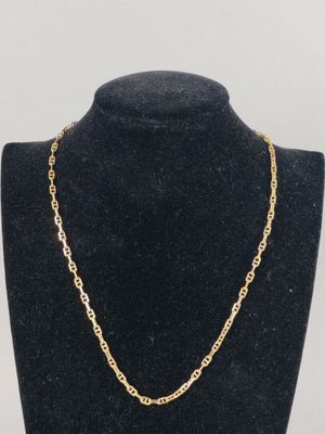 a gold chain necklace on a mannequin neck