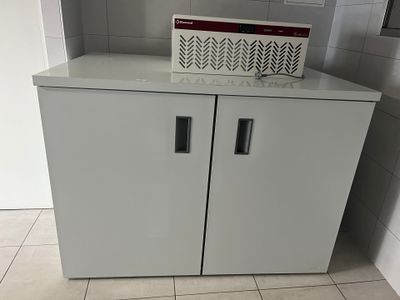 une armoire blanche à deux portes, surmontée d'une pancarte