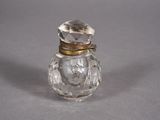 an antique glass perfume bottle with a gold lid on a gray surface