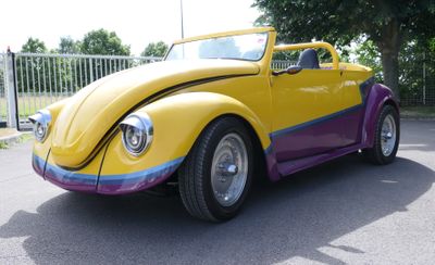 yellow and purple vw buggy parked in a parking lot next to a fence