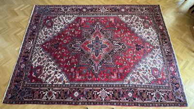 un tapis oriental posé sur un parquet, avec une chaise à l'arrière-plan