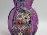 un vase violet orné de fleurs, posé sur une table