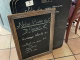tables and chairs in a restaurant with a chalk board sign on the floor