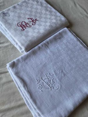 Deux serviettes ornées de monogrammes sont posées sur un lit.