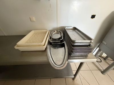 Plusieurs plateaux de nourriture sont posés sur une table en métal dans une cuisine