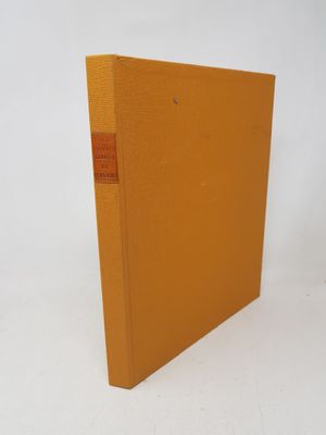 an orange book sitting on top of a white table next to a white wall