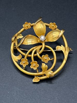 une image représentant une broche en or ornée de fleurs et de feuilles