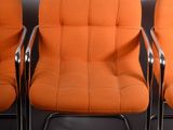 three orange chairs sitting next to each other against a white wall