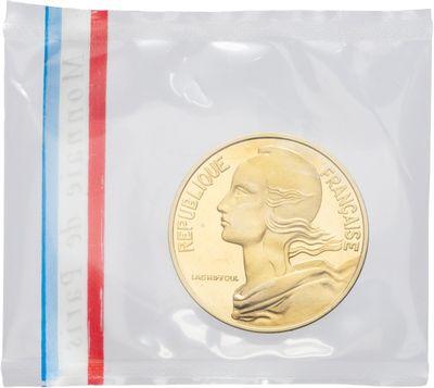 un gros plan d'une pièce de monnaie dans un sachet en plastique posé sur une surface blanche