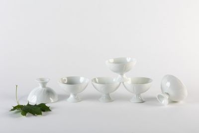 cinq vases blancs posés les uns à côté des autres sur une surface blanche