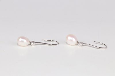 une paire de boucles d'oreilles en perles blanches avec des crochets en argent, sur un fond blanc