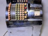 une caisse enregistreuse à l'ancienne sur laquelle sont posées de nombreuses pièces de monnaie