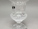 a glass vase that is on a stand on a table