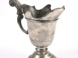 a silver cup with a handle on a pedestal