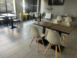 des tables et des chaises dans un restaurant où est accrochée une télévision à écran plat au mur