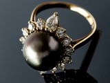a close up of a black pearl and diamond ring on a black surface