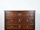 une commode ancienne posée sur un parquet dans une pièce