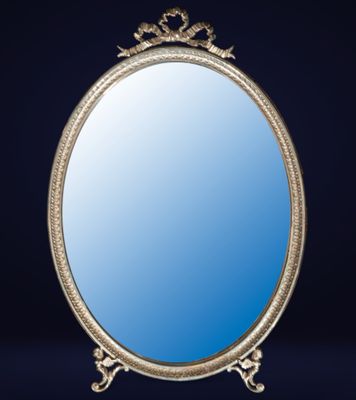 un miroir au cadre en argent ouvragé sur fond bleu foncé