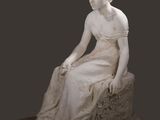 statue en marbre représentant une femme assise sur un rocher