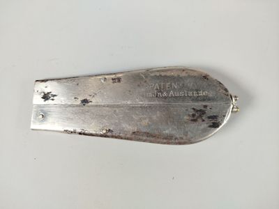 une cuillère en argent avec un manche en métal posée sur une surface blanche