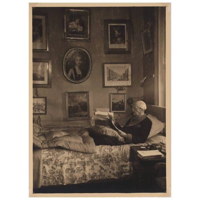 photographie en noir et blanc d'une femme assise sur un lit en train de lire un livre
