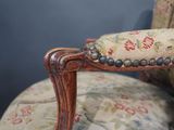 a close up of a wooden chair with a floral upholstered seat