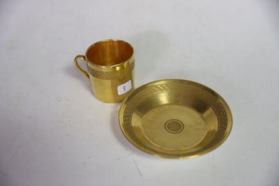 une tasse et une soucoupe dorées posées sur une table blanche