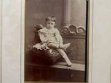 an old photo of a young boy sitting on a bench