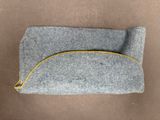 pochette en feutre gris avec une fermeture éclair jaune sur fond marron