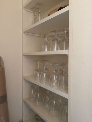 une étagère avec des verres à vin et une planche de surf dans un coin