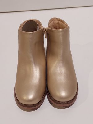a close up of a pair of gold ankle boots on a white surface