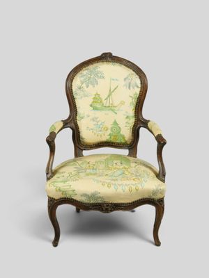 une vieille chaise dont le dossier est recouvert d'un tissu vert et blanc
