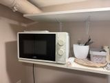 a microwave sitting on a shelf in the corner of a room