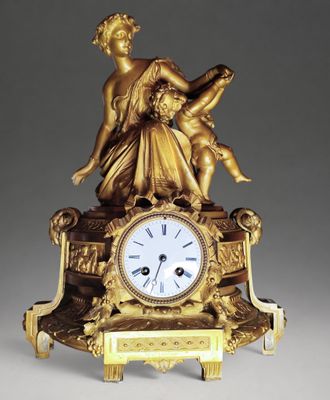 a gold clock with a statue on top of it