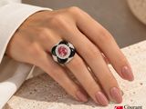 woman ' s hand with a pink and black ring on a table