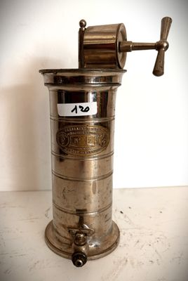 un moulin à café ancien posé sur une table, avec une étiquette de prix dessus