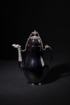 black and white photograph of a teapot with a bird on the handle