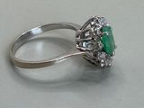 a ring with a green stone surrounded by white diamonds
