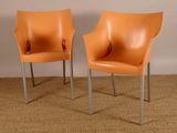 une paire de fauteuils en cuir orange aux pieds chromés, posés sur un espace recouvert de moquette