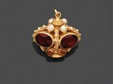 un pendentif en or orné de grenats et de perles sur un fond noir