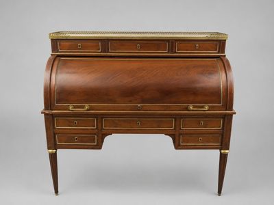 an antique writing desk with brass trimming and drawers