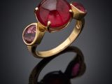 a gold ring with a red stone and two pink stones